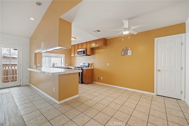 kitchen featuring kitchen peninsula, stainless steel appliances, light tile patterned floors, and ceiling fan