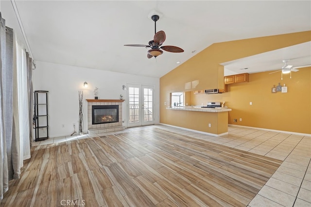 unfurnished living room with vaulted ceiling, light hardwood / wood-style flooring, french doors, and ceiling fan