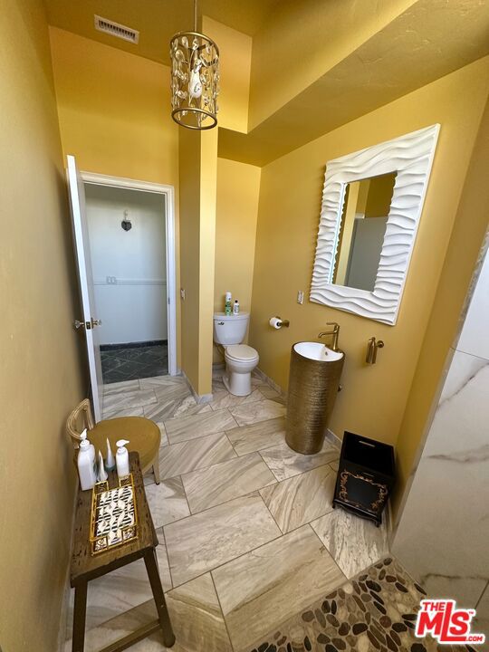 bathroom with a chandelier and toilet