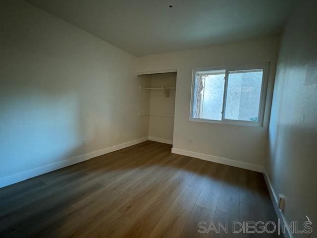 unfurnished bedroom with dark wood-type flooring and a closet