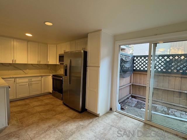 kitchen featuring backsplash, white cabinetry, and stainless steel appliances