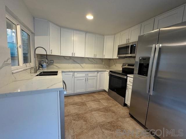 kitchen featuring white cabinets, sink, decorative backsplash, light stone countertops, and appliances with stainless steel finishes