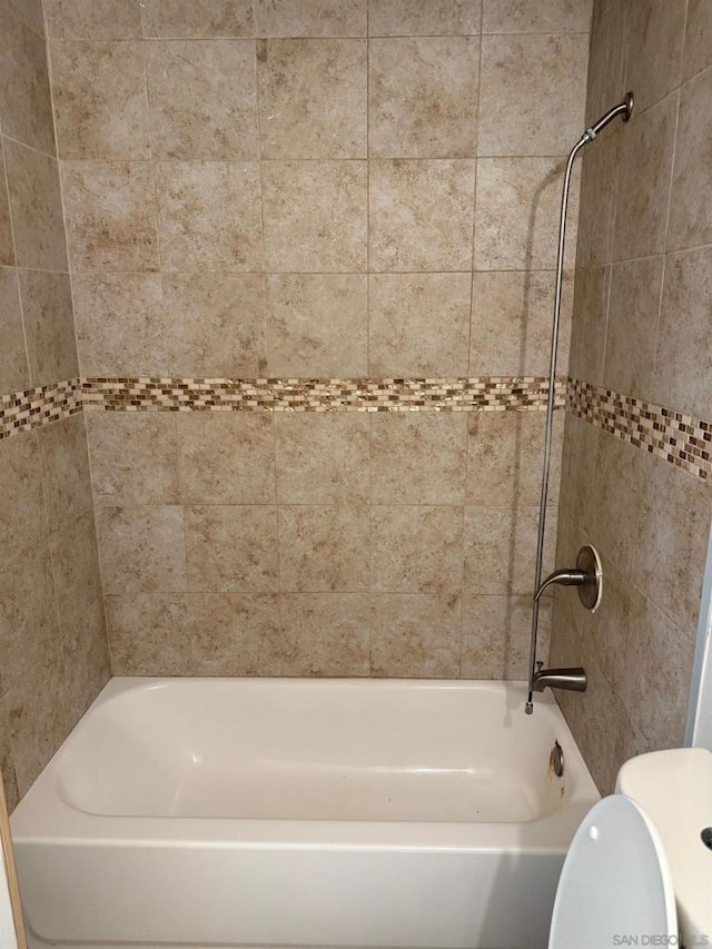 bathroom with toilet and tiled shower / bath