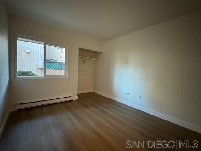 unfurnished bedroom featuring a closet, hardwood / wood-style floors, and a baseboard radiator