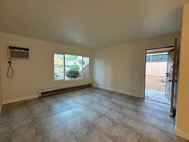 spare room featuring an AC wall unit and a baseboard heating unit