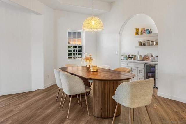 dining area featuring wood-type flooring, indoor bar, and beverage cooler