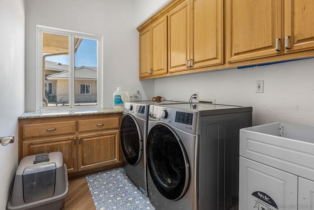 laundry area with hardwood / wood-style flooring, washer and dryer, and cabinets