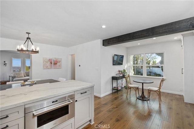 kitchen featuring stainless steel oven, light stone countertops, decorative light fixtures, dark hardwood / wood-style flooring, and white cabinetry