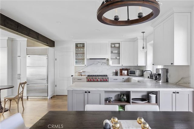 kitchen featuring sink, appliances with stainless steel finishes, decorative light fixtures, light hardwood / wood-style floors, and white cabinetry