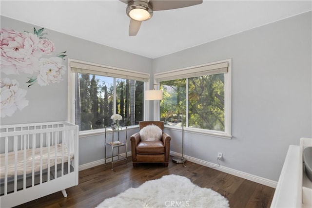 bedroom featuring a nursery area, dark hardwood / wood-style floors, and ceiling fan