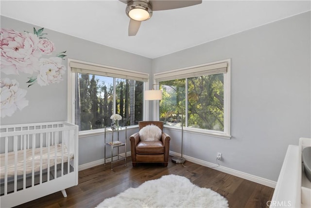 bedroom featuring baseboards, a crib, a ceiling fan, and wood finished floors