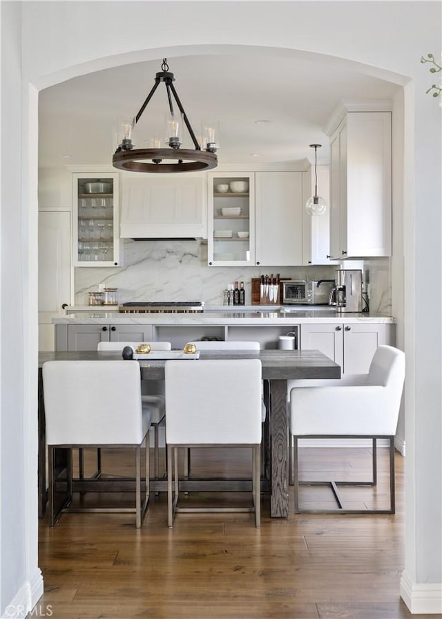 kitchen with white cabinetry, dark wood-style floors, decorative backsplash, and glass insert cabinets