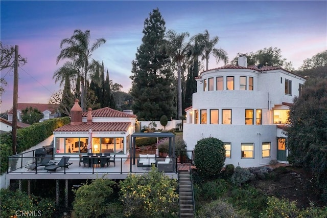 back house at dusk featuring a deck