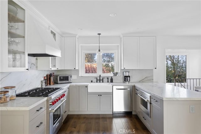 kitchen with a wealth of natural light, sink, hanging light fixtures, stainless steel appliances, and kitchen peninsula