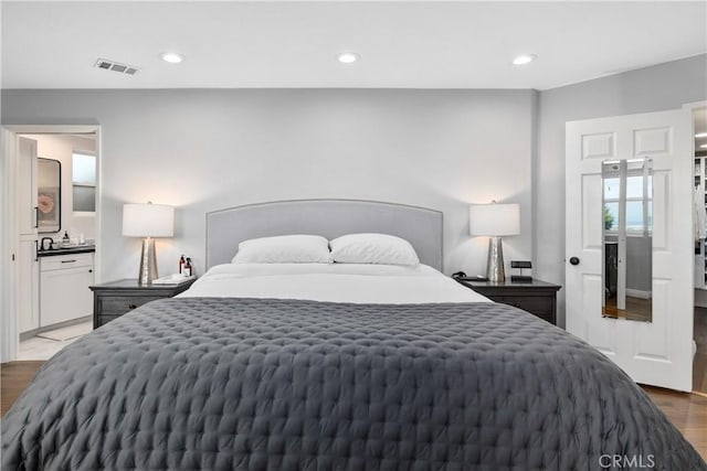 bedroom with wood-type flooring and ensuite bath