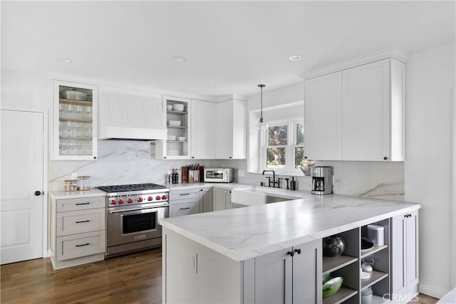 kitchen with kitchen peninsula, decorative light fixtures, white cabinets, and premium stove