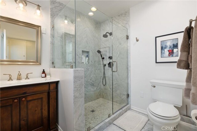 bathroom featuring vanity, toilet, and a shower with door