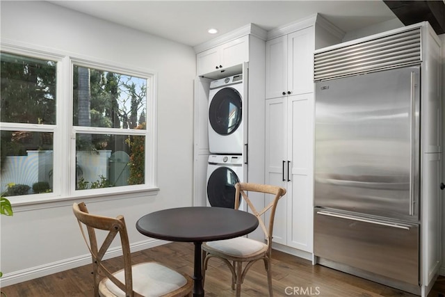 interior space featuring stainless steel built in refrigerator, stacked washer and dryer, white cabinetry, and dark hardwood / wood-style floors