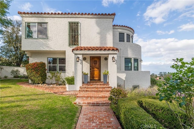 mediterranean / spanish-style home featuring a front lawn, stucco siding, and a tile roof