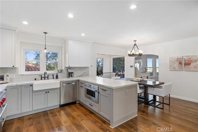 kitchen featuring a sink, a peninsula, stainless steel appliances, and a healthy amount of sunlight
