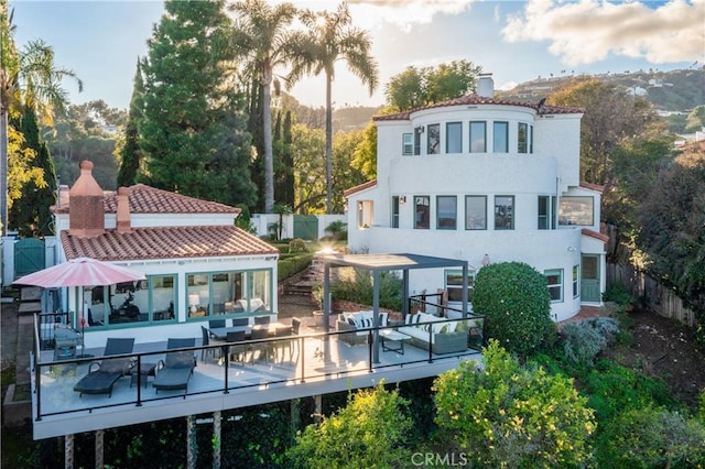 back of property featuring outdoor dining area, a chimney, a wooden deck, and a fenced backyard