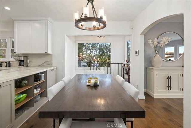 dining room featuring a notable chandelier, a healthy amount of sunlight, and dark wood-type flooring