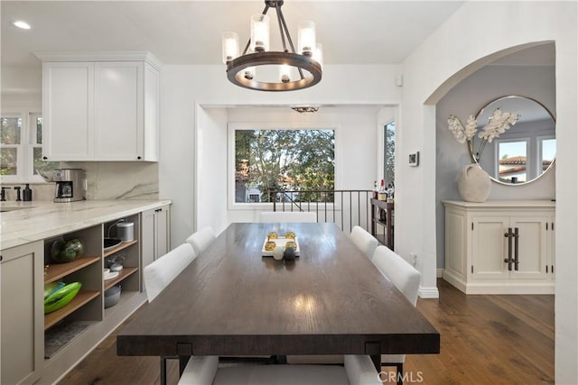 dining room with arched walkways, a chandelier, recessed lighting, and dark wood-type flooring