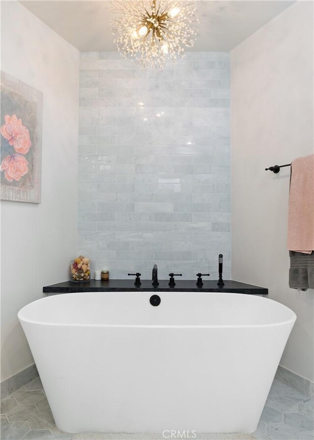 bathroom featuring a notable chandelier and a bath