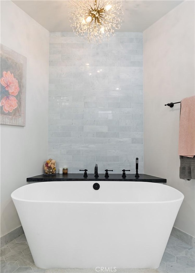 bathroom featuring a notable chandelier, baseboards, and a freestanding tub