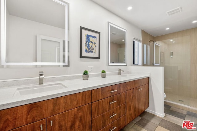 bathroom featuring toilet, tile patterned flooring, a tile shower, and vanity