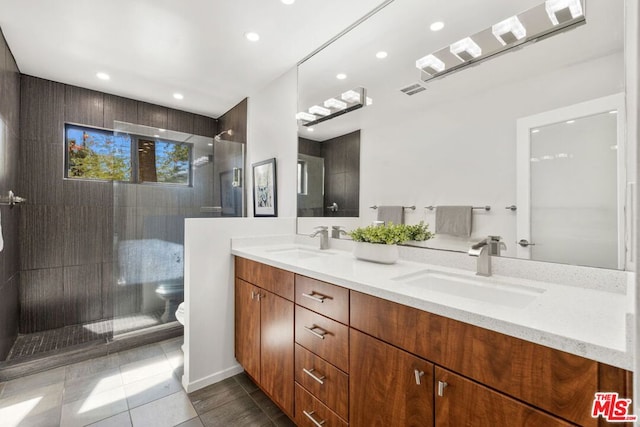 bathroom featuring toilet, a tile shower, tile patterned floors, and vanity