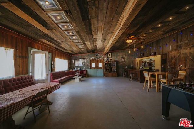 interior space with ceiling fan, wooden walls, concrete floors, and wooden ceiling