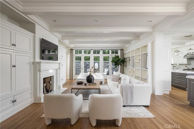 living room with french doors, light hardwood / wood-style flooring, ornamental molding, a fireplace, and beamed ceiling