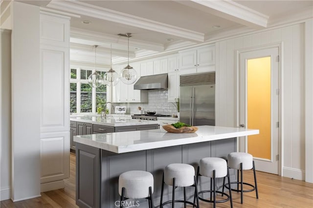 kitchen with a center island with sink, white cabinets, extractor fan, and built in refrigerator