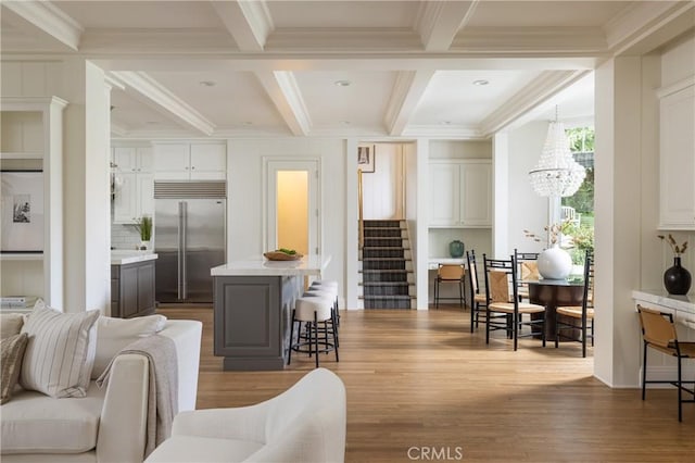 living room with beamed ceiling, light hardwood / wood-style floors, crown molding, and coffered ceiling