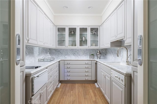 kitchen featuring decorative backsplash, white dishwasher, sink, light hardwood / wood-style flooring, and white cabinetry