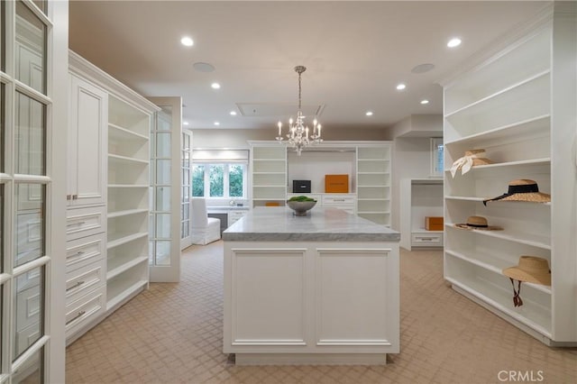 kitchen featuring a notable chandelier, light carpet, white cabinets, decorative light fixtures, and light stone counters