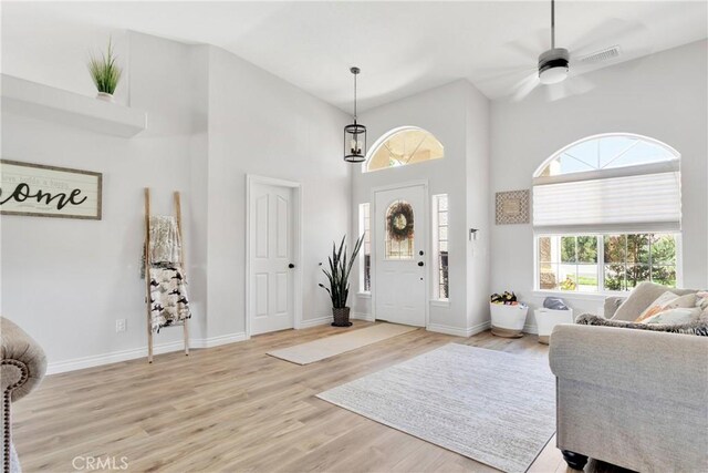 entryway featuring ceiling fan, light wood-type flooring, and a towering ceiling