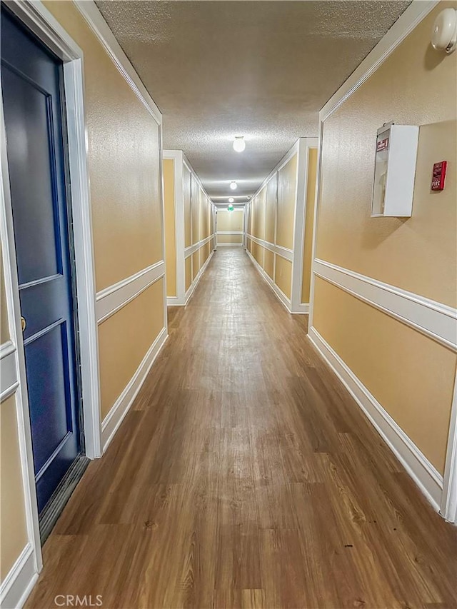 hallway with a textured ceiling and hardwood / wood-style floors