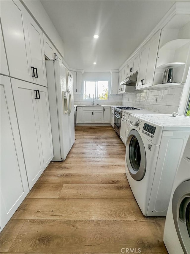 laundry room featuring light hardwood / wood-style floors, washer / dryer, and sink