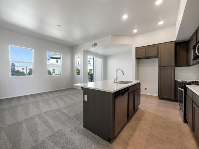 kitchen with light carpet, dark brown cabinetry, stainless steel appliances, sink, and an island with sink