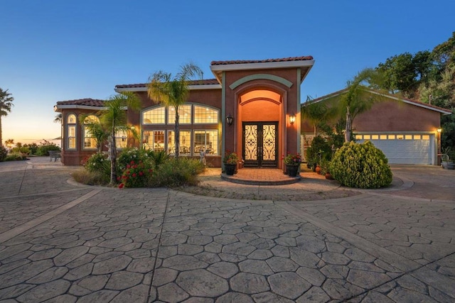 mediterranean / spanish-style house with a garage and french doors