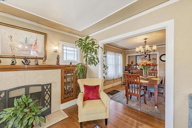 living area featuring an inviting chandelier, ornamental molding, hardwood / wood-style floors, and a tile fireplace