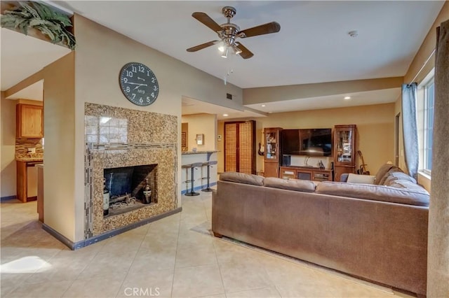 tiled living room featuring a fireplace, ceiling fan, and vaulted ceiling