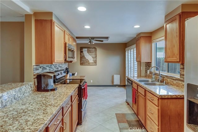 kitchen featuring tasteful backsplash, stainless steel appliances, light stone countertops, and sink