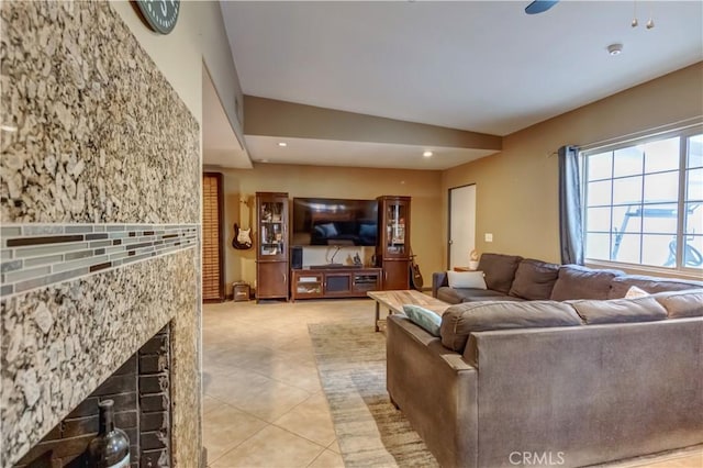 tiled living room featuring ceiling fan and a fireplace