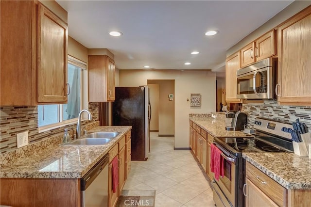 kitchen with light stone counters, appliances with stainless steel finishes, sink, and tasteful backsplash