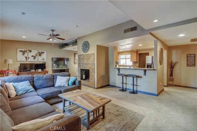 living room featuring light tile patterned floors, a fireplace, and ceiling fan