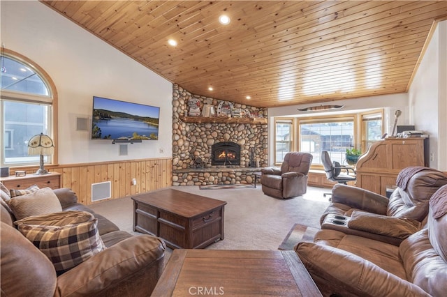 living room featuring high vaulted ceiling, wood ceiling, a fireplace, wood walls, and carpet