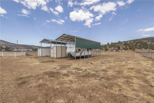 view of outbuilding with a mountain view, a carport, and a rural view